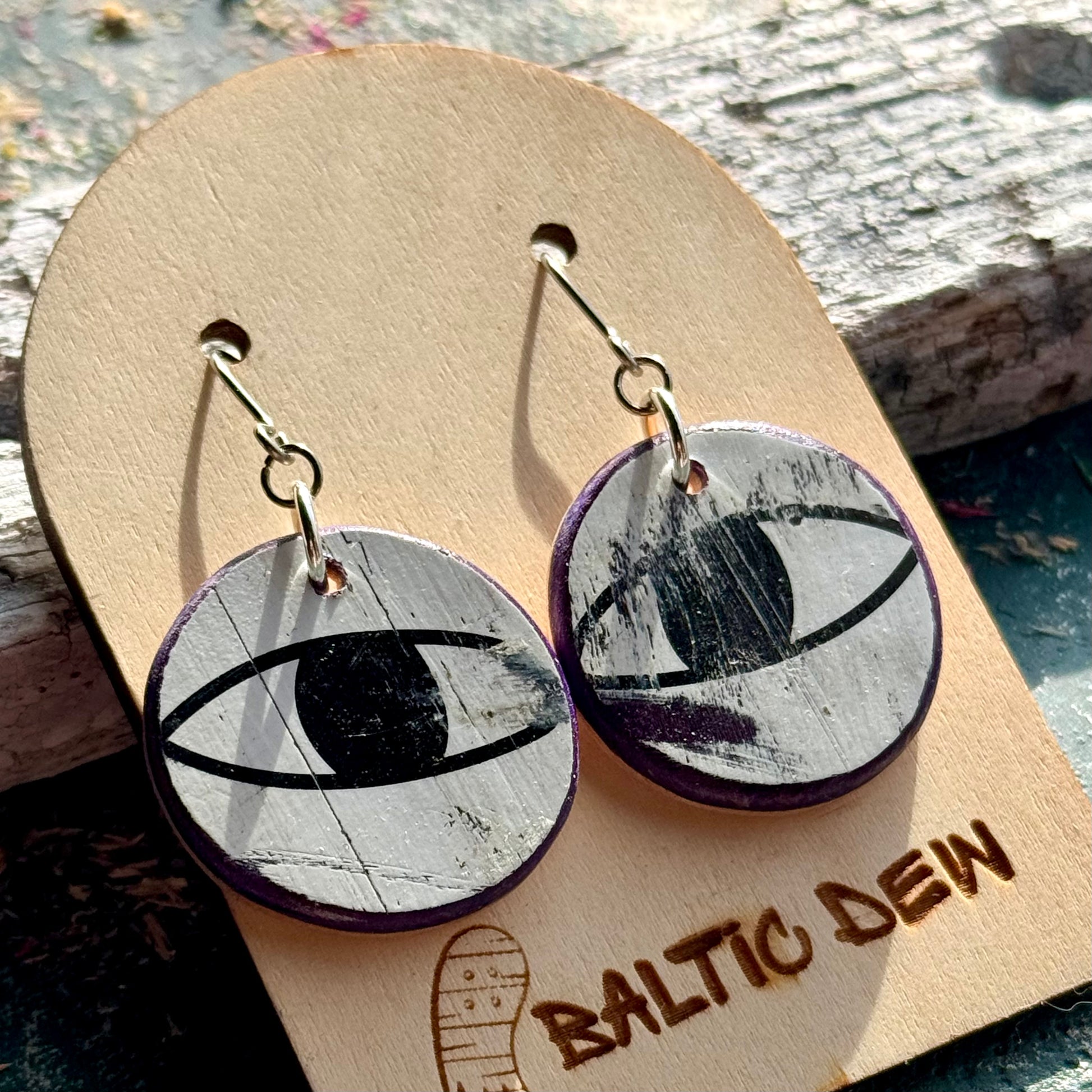 Black and white recycled skateboard wood drop earrings showing cat eyes from the deck graphic