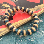 Blue and black wood bead bracelet in a full round on a painted skateboard deck, handmade by Baltic Dew.