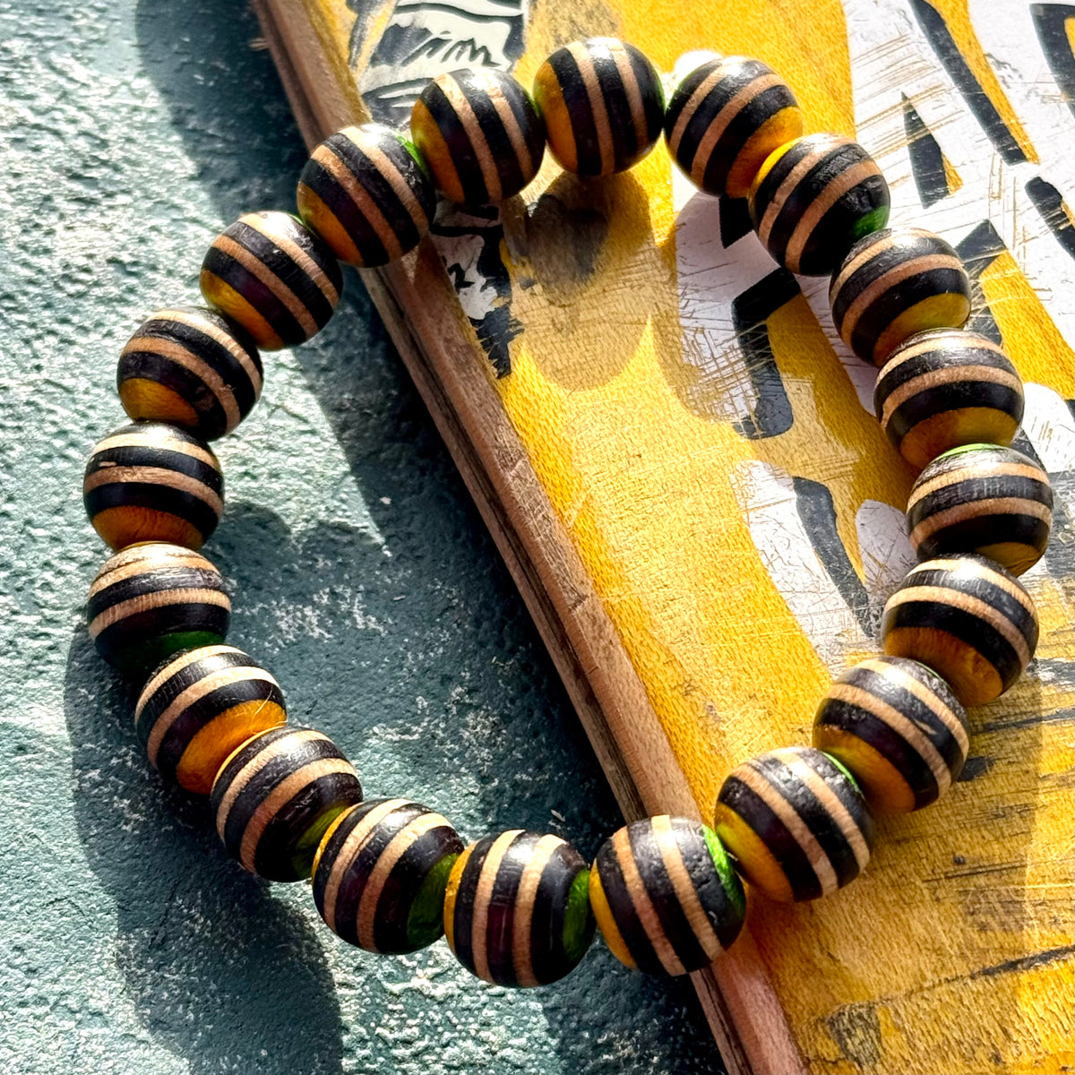 Twenty black, yellow and green striped beads cut from recycled skateboard maple, handmade by Baltic Dew.