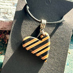 Black and natural striped wooden heart pendant cut from recycled skateboard maple on a waxed cord.