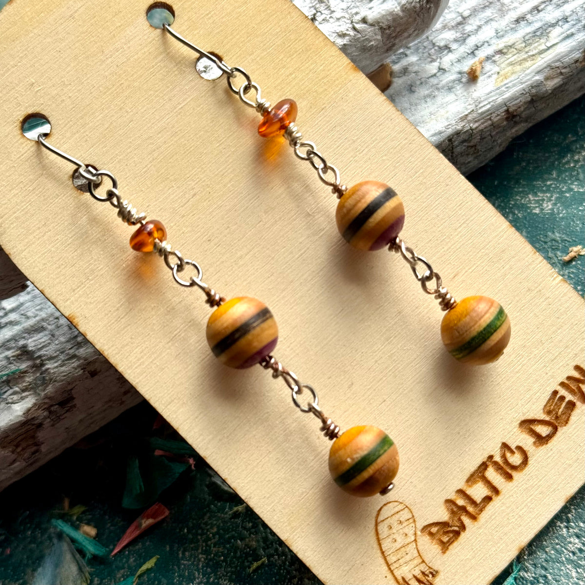 Long drop earrings with two striped recycled skateboard wood beads and Lithuanian amber, on a card