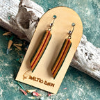Red and orange striped recycled skateboard wood long drop earrings shown on a Baltic Dew card