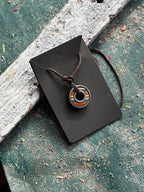 Skateboard bearing pendant with orange and natural maple layers on an adjustable waxed cotton cord.