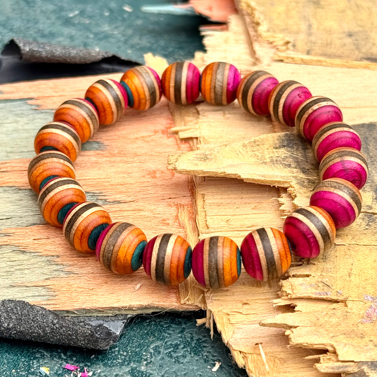 Orange and pink wood bead bracelet from recycled skateboard maple on a broken deck, the layers striping every bead.