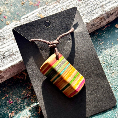 Striped skateboard wood pendant in orange, pink, green and teal on an adjustable cord, by Baltic Dew.