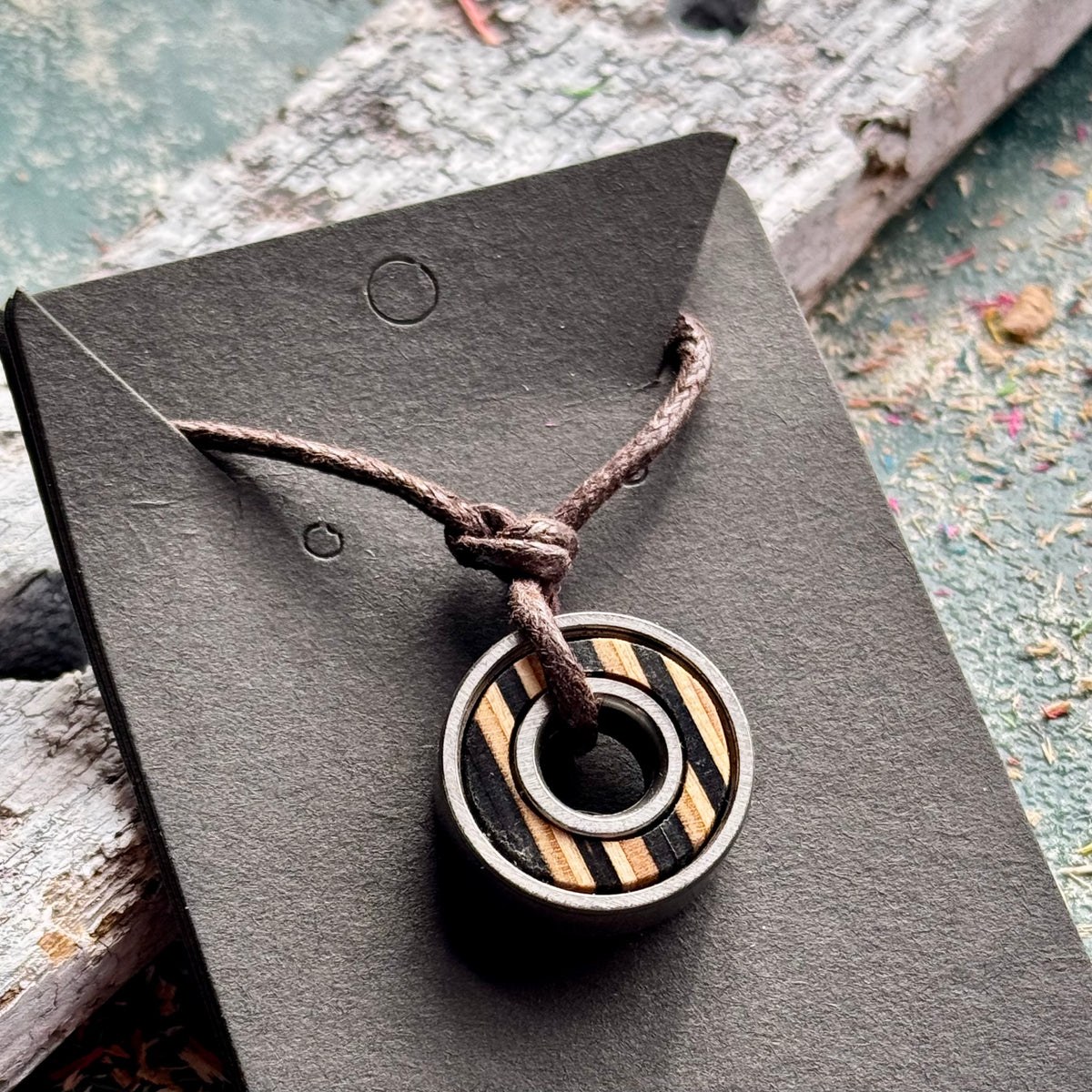 Black and natural maple skateboard bearing pendant on a brown waxed cotton cord, handmade by Baltic Dew.