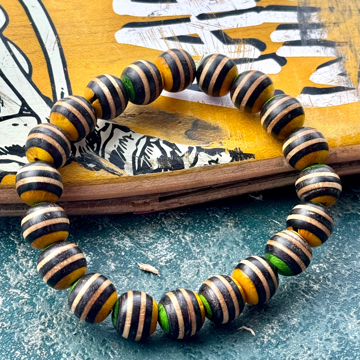 Bead bracelet in black, yellow and green made from a recycled skateboard deck in the UK.