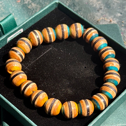 Close-up of a Yellow and Blue Skateboard Bracelet made from recycled skateboard wood beads with natural and painted stripes.