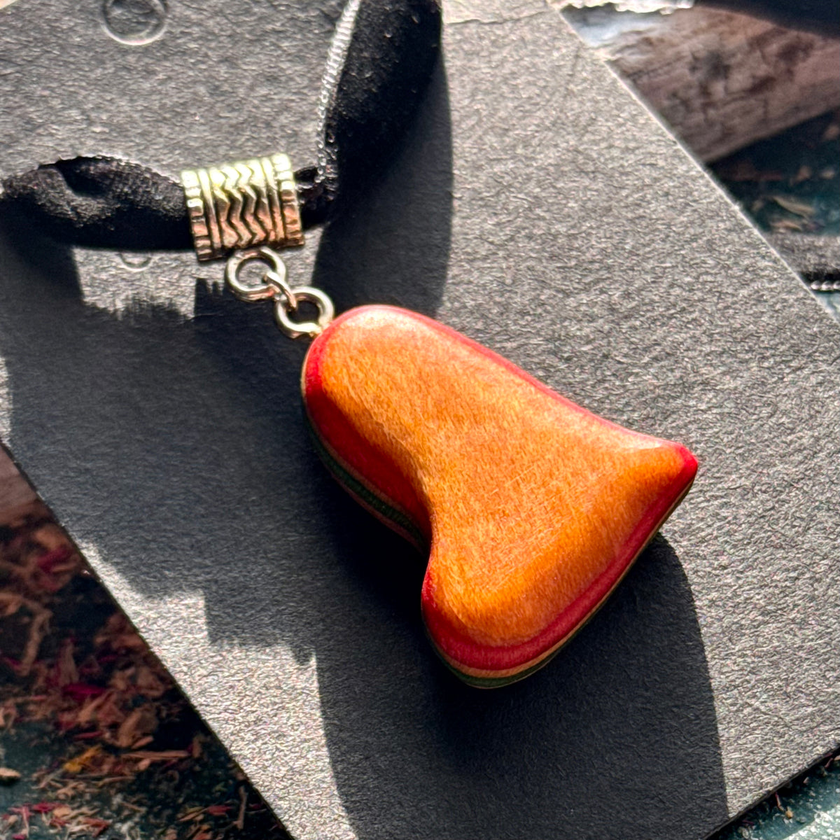 Orange heart pendant in recycled skateboard maple on a black velvet choker, handmade by Baltic Dew.