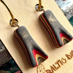 Close view of black and red recycled skateboard wood drops on gold hoops, layers curving to a point