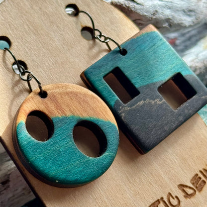 Close view of teal recycled skateboard earrings with cut-out holes and rectangular slots