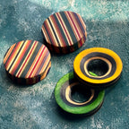 Striped plugs beside yellow and green tunnels, all cut from recycled skateboard maple.