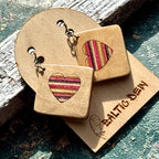 Beige recycled skateboard square drop earrings with heart cut-outs, showing pink, black and cream layered maple.