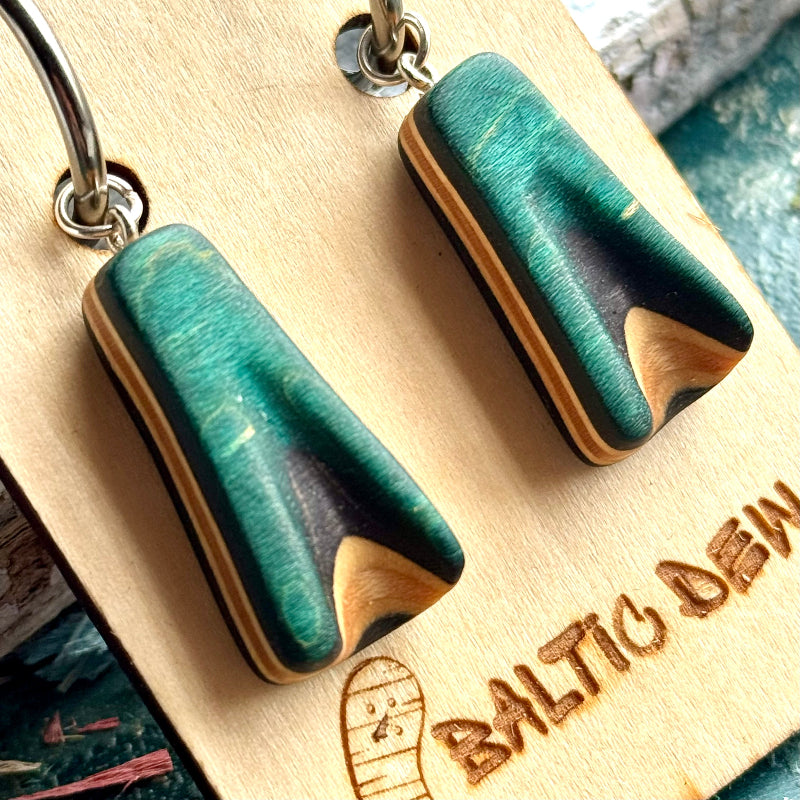 Teal skateboard wood hoop drops on silver hoops, the carved face exposing black and natural maple layers