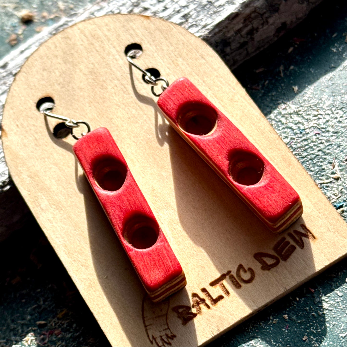 Red skateboard wood bar earrings on surgical steel hooks, pale maple layers showing along the edge