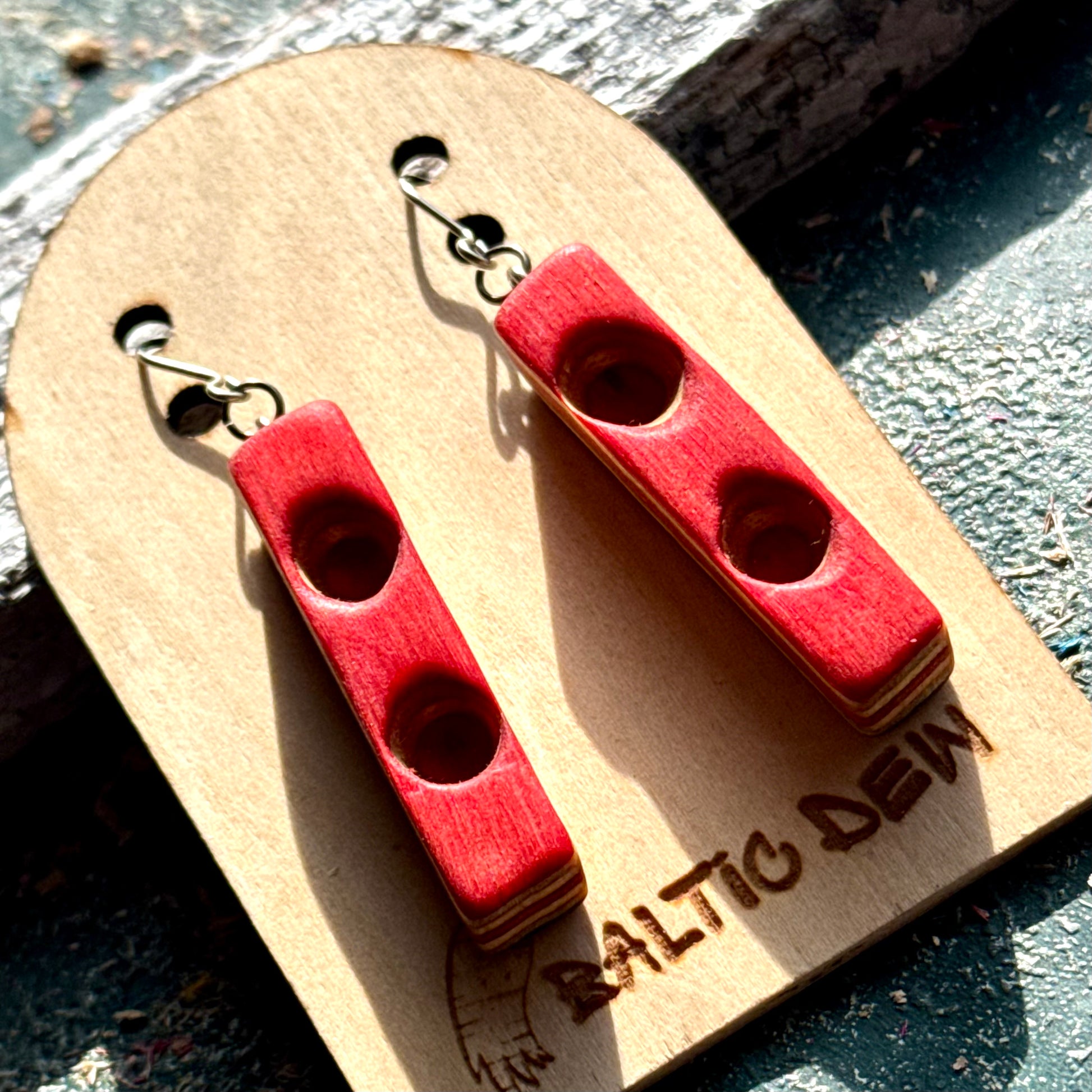 Red skateboard wood bar earrings on surgical steel hooks, pale maple layers showing along the edge