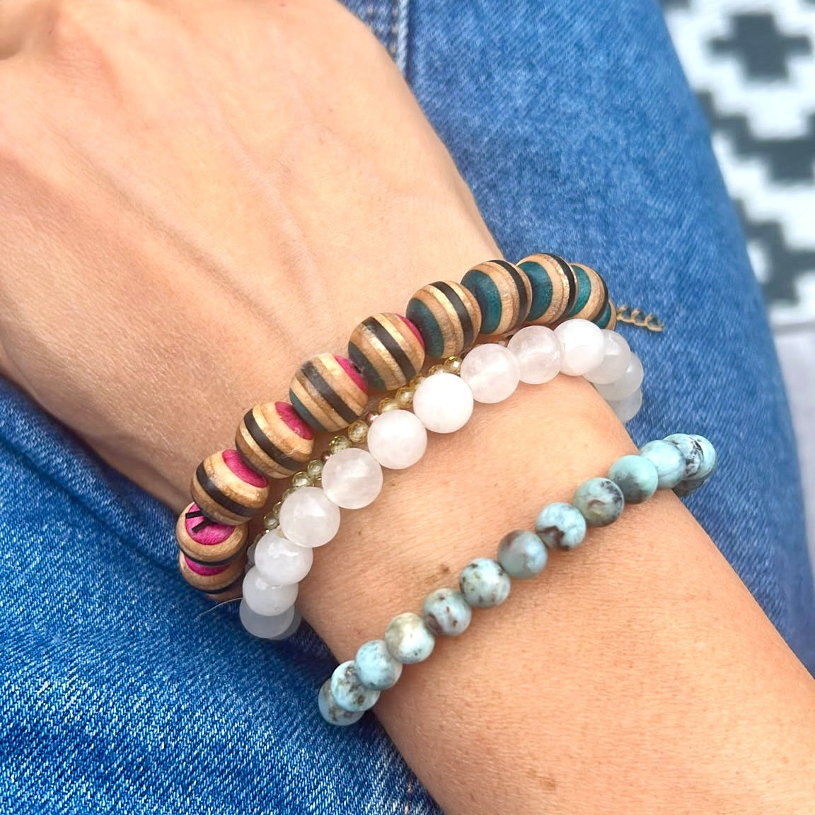 Skateboard wood bead bracelet worn on a wrist alongside other bracelets