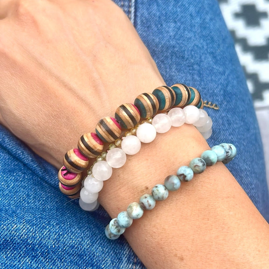 Skateboard wood bead bracelet worn on a wrist alongside other bracelets