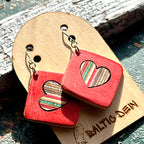 Red recycled skateboard square drop earrings with heart cut-outs, showing cream, orange and pink layered maple.