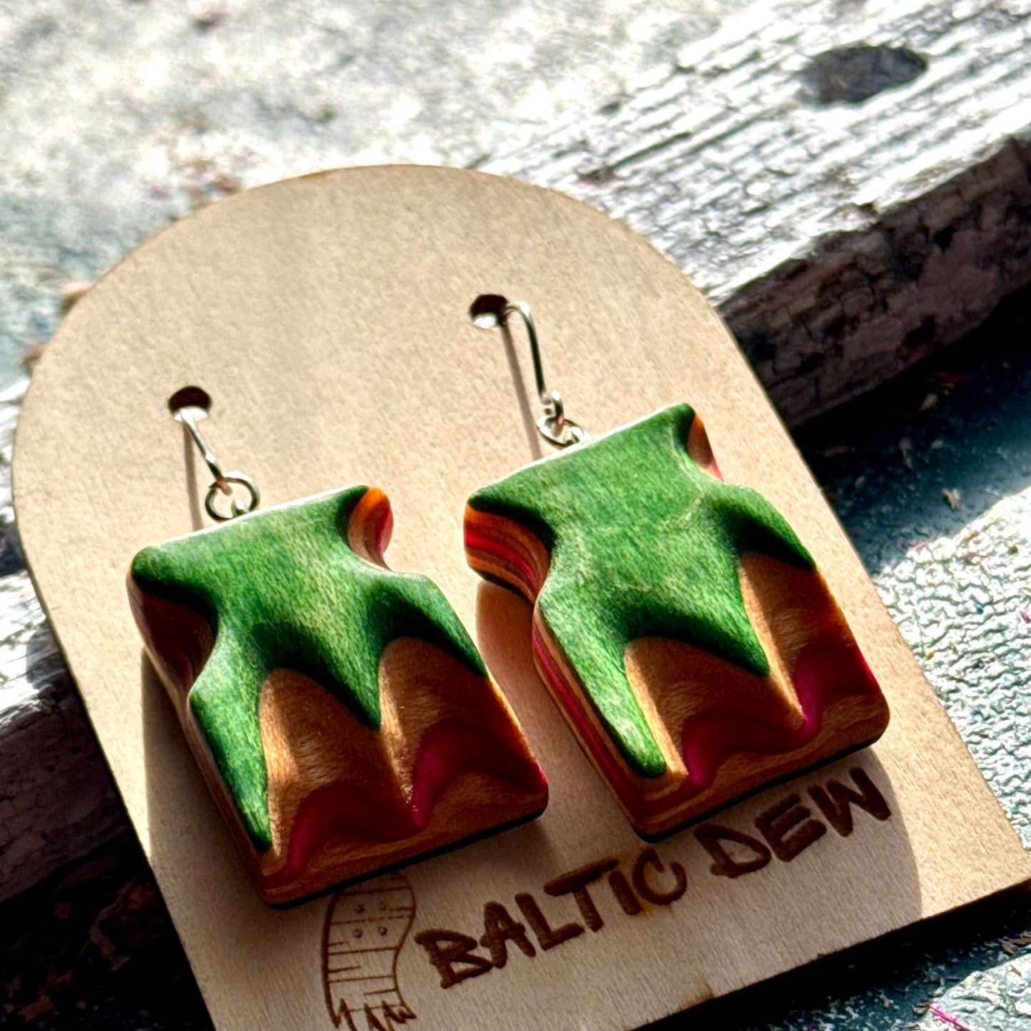 Green and pink recycled skateboard wood wave earrings with the deck layers carved through