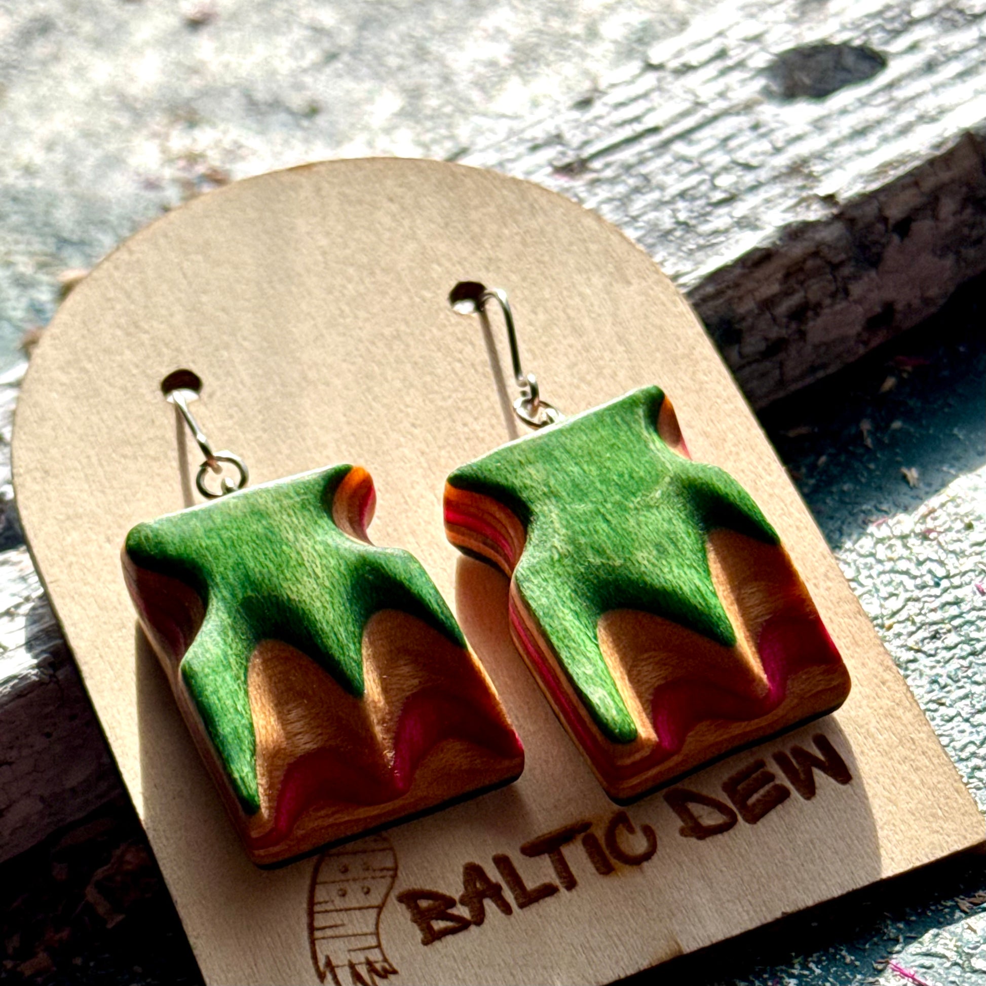 Green and pink recycled skateboard wood wave earrings with the deck layers carved through
