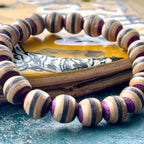 Wooden bead bracelet cut from a recycled skateboard deck, with purple, brown and black layers on every bead.
