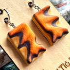 Close view of orange and purple carved wave earrings showing the deck's colour bands
