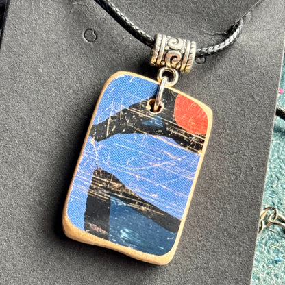 Blue and orange rectangular wooden pendant showing a fragment of the skateboard deck's flower graphic.