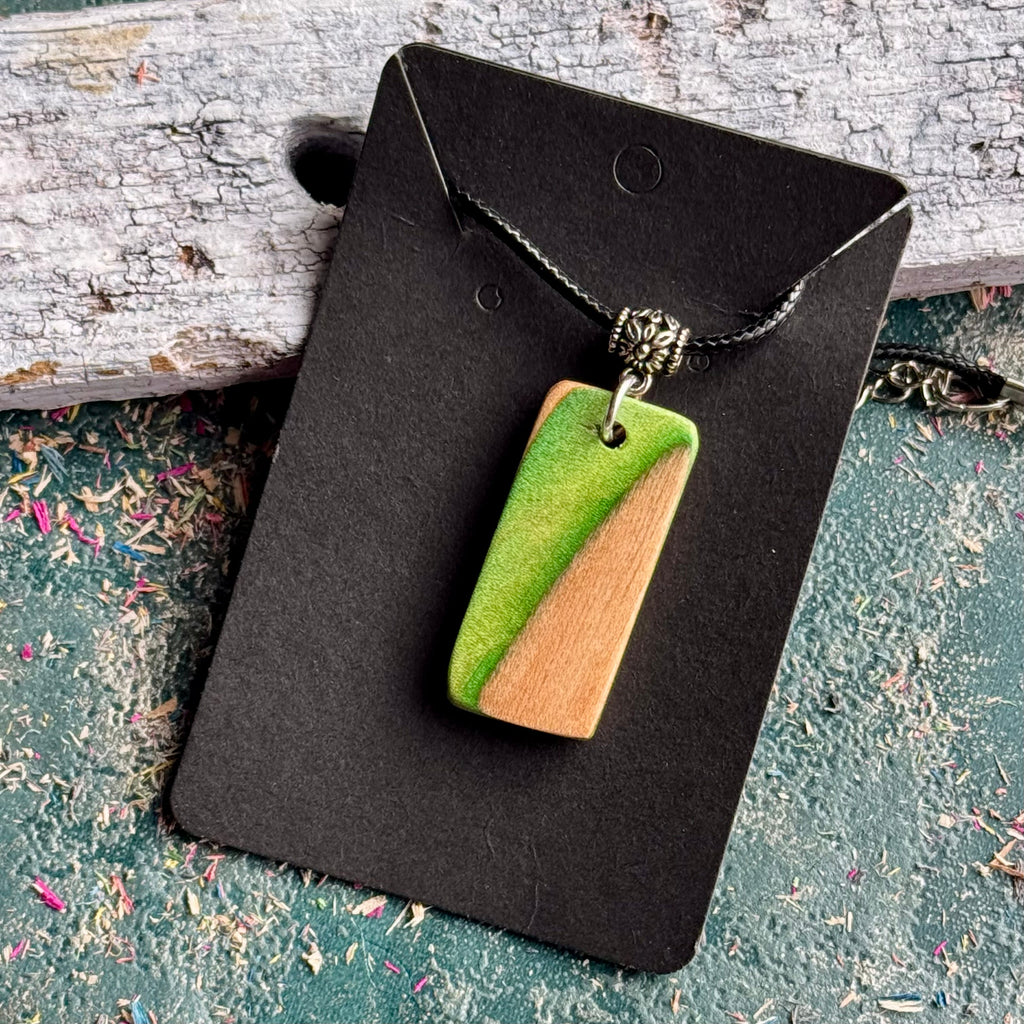 Green and natural maple skateboard wood pendant on a black waxed cord, handmade by Baltic Dew.