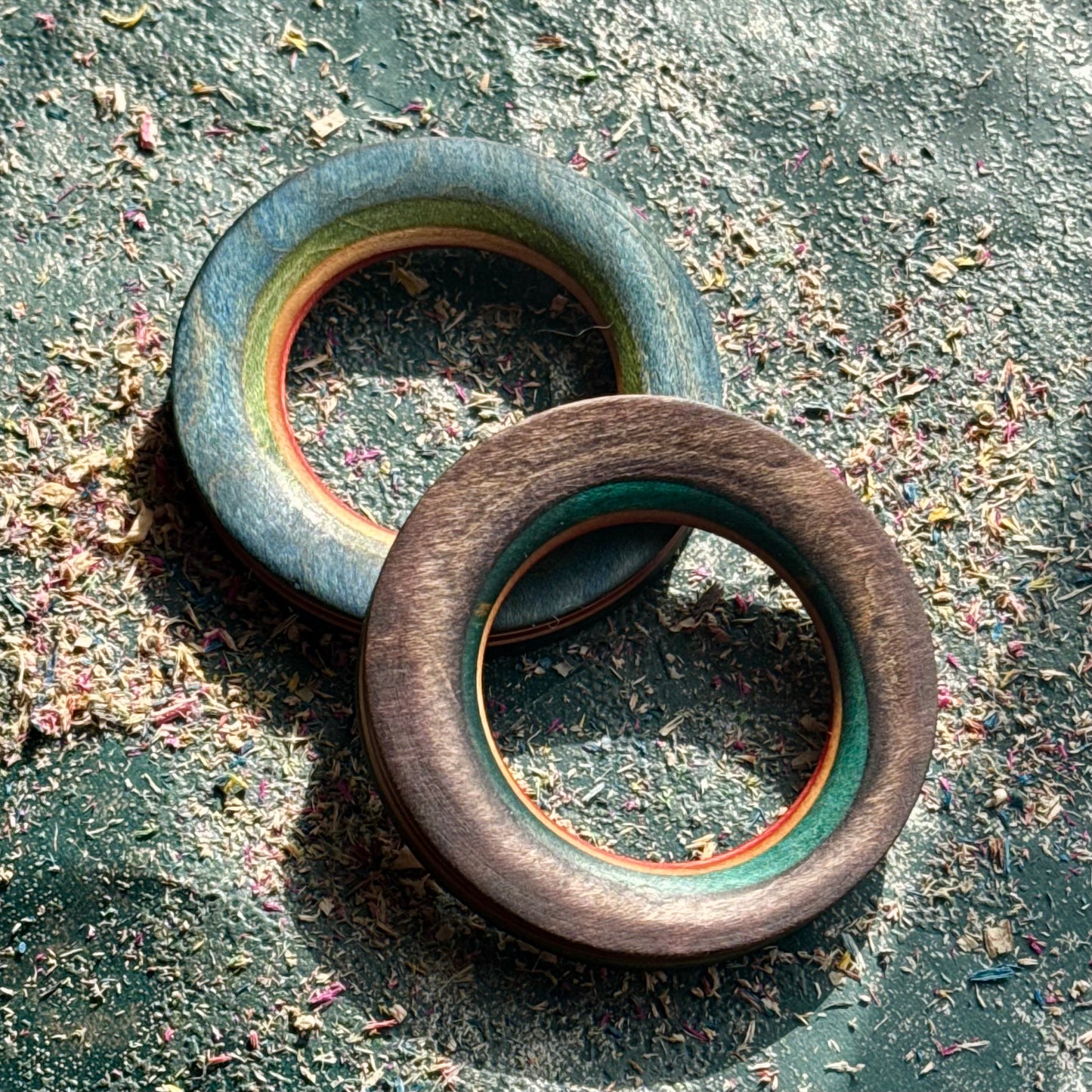 Pale blue and brown wooden tunnels from a recycled skateboard, resting on a textured surface.