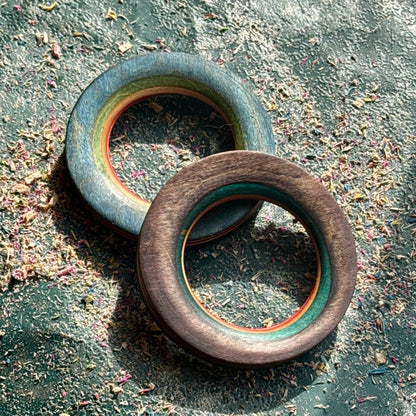 Pale blue and brown wooden tunnels from a recycled skateboard, resting on a textured surface.