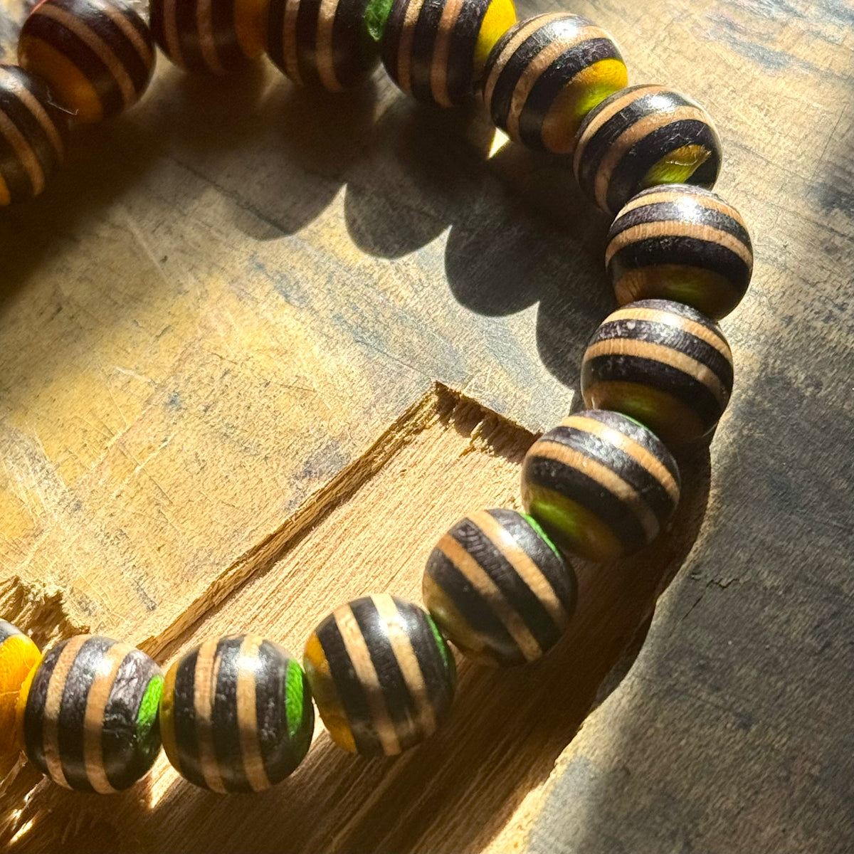 Black, yellow and green recycled skateboard wood bead bracelet, handmade by Baltic Dew.