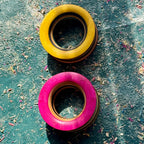 Yellow and pink tunnels in recycled skateboard maple, showing the deck's colour layers.