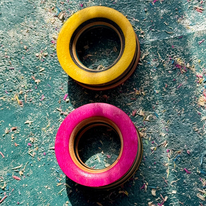 Yellow and pink tunnels in recycled skateboard maple, showing the deck's colour layers.