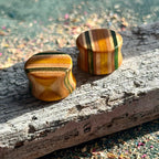 Green and yellow double flare ear plugs at 16mm in layered skateboard maple.