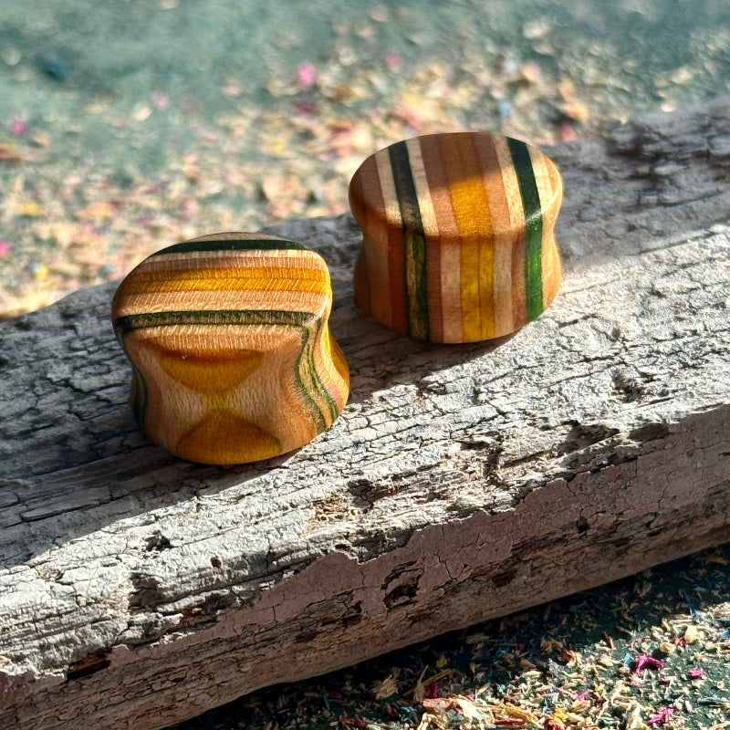 Green and yellow double flare ear plugs at 16mm in layered skateboard maple.
