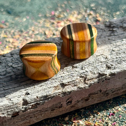 Green and yellow double flare ear plugs at 16mm in layered skateboard maple.