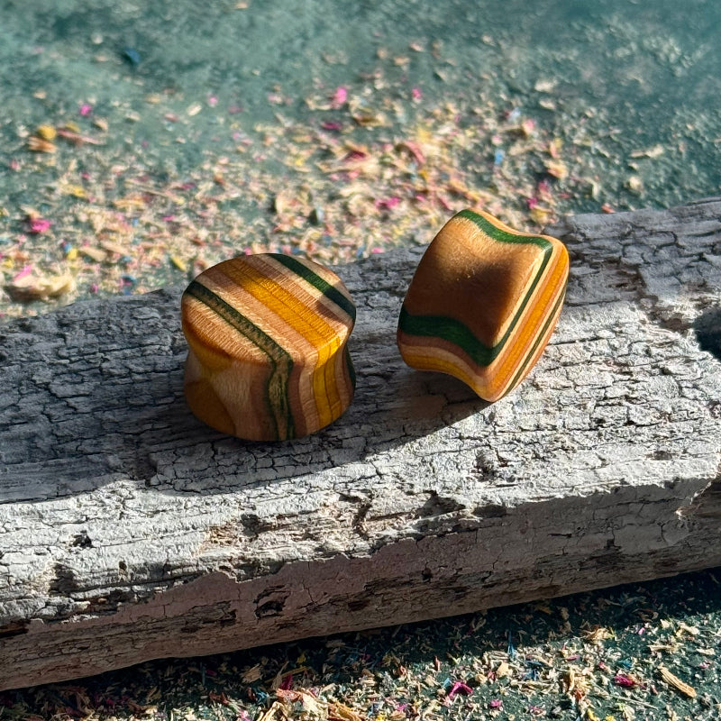 Green and Yellow Double Flare Wooden Ear Plugs 16mm with striped natural wood patterns on weathered surface