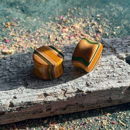 Green and Yellow Double Flare Wooden Ear Plugs 16mm with striped natural wood patterns on weathered surface