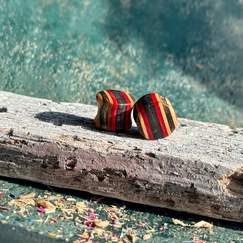 Red and black double flare ear plugs at 10mm in recycled skateboard maple, handmade by Baltic Dew.