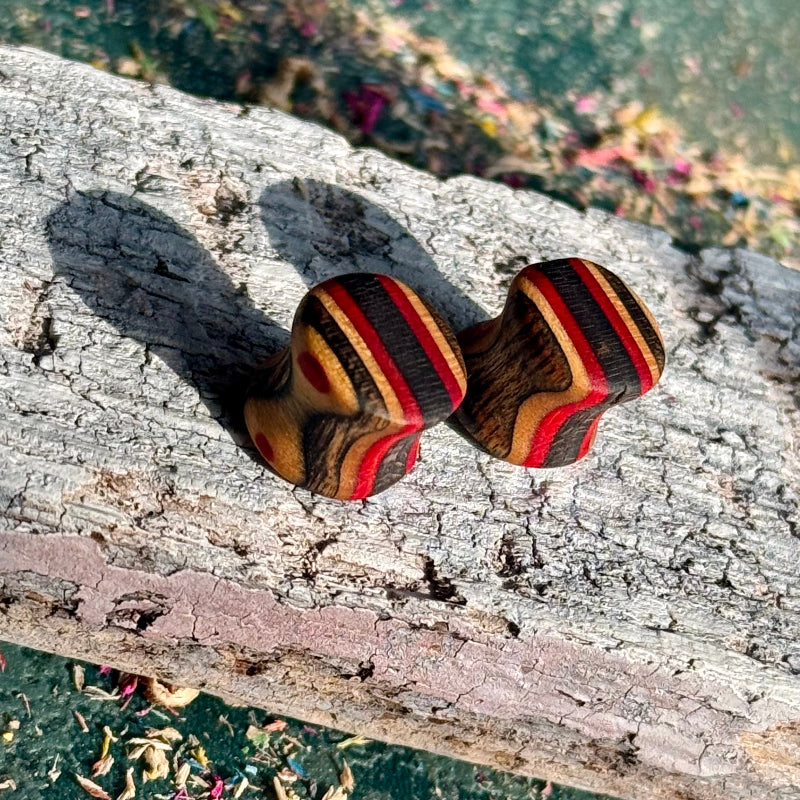 Red and black 10mm ear plugs angled to show the layered stripes through the wall.