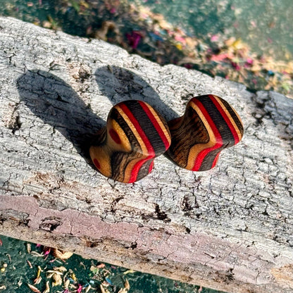 Red and black 10mm ear plugs angled to show the layered stripes through the wall.