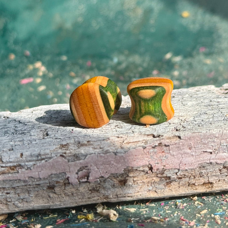 Green and yellow double flare ear plugs at 10mm, cut from a recycled skateboard deck.