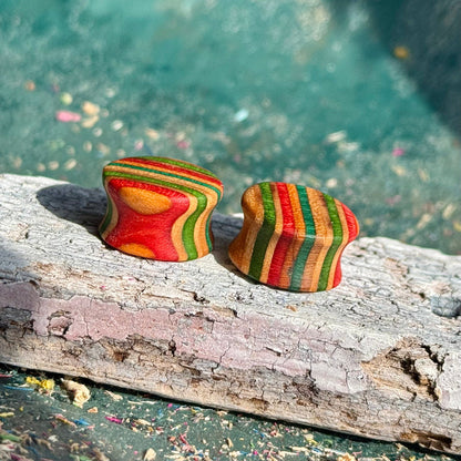 Green, red and orange 16mm ear plugs close up, three colours stacked through the wall.