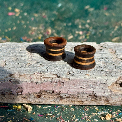 Brown and Grey Flare Wooden Ear Tunnels 10mm with striped design on rustic wooden surface outdoors