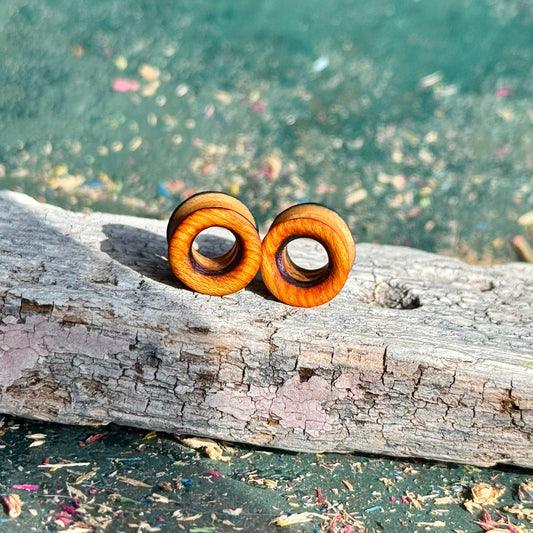 Orange, Purple and Blue Double Flare Wooden Ear Tunnels 10mm shown on a textured log background in natural light