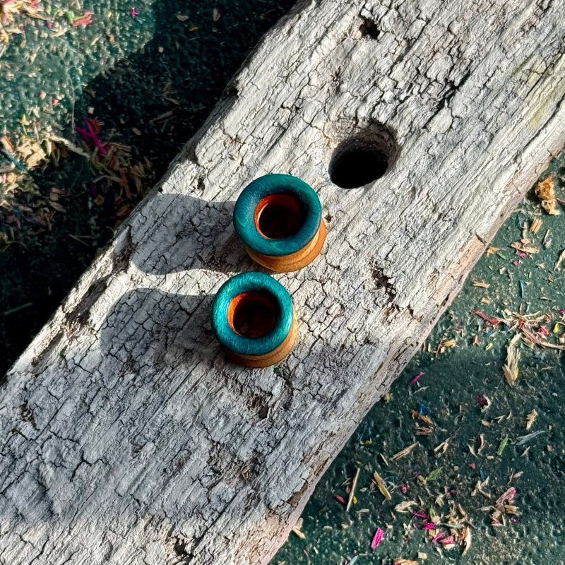 Blue, Orange and Yellow Double Flare Wooden Ear Tunnels 10mm placed on weathered wooden surface with natural lighting