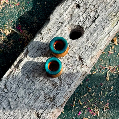 Blue, Orange and Yellow Double Flare Wooden Ear Tunnels 10mm placed on weathered wooden surface with natural lighting