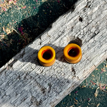 Yellow, Orange and Blue Double Flare Wooden Ear Tunnels 10mm displayed on textured wood in natural light outdoors