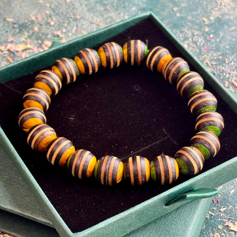 Yellow, green and black striped bead bracelet in a green jewellery box.